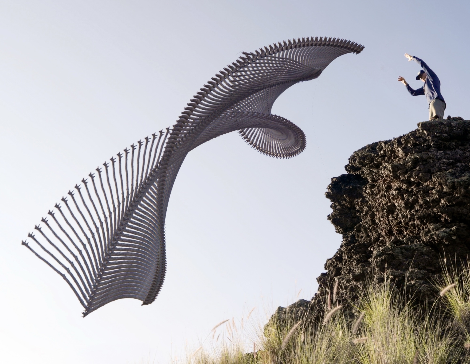 Temporal sculpture arcing off a rock outcrop beside a standing figure